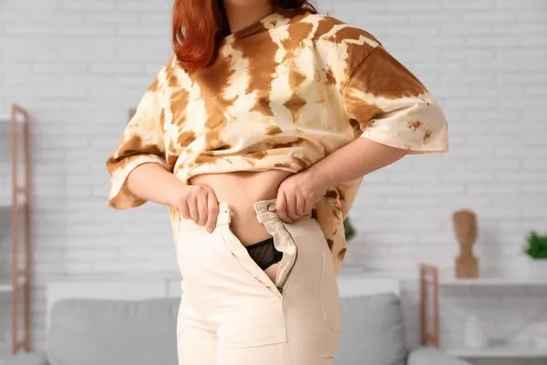 Image of woman trying to do her trousers up after pregnancy weight gain Middleton Park
